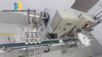 Linear filling machine with 4 stainless steel screw-on nozzles for bottles.